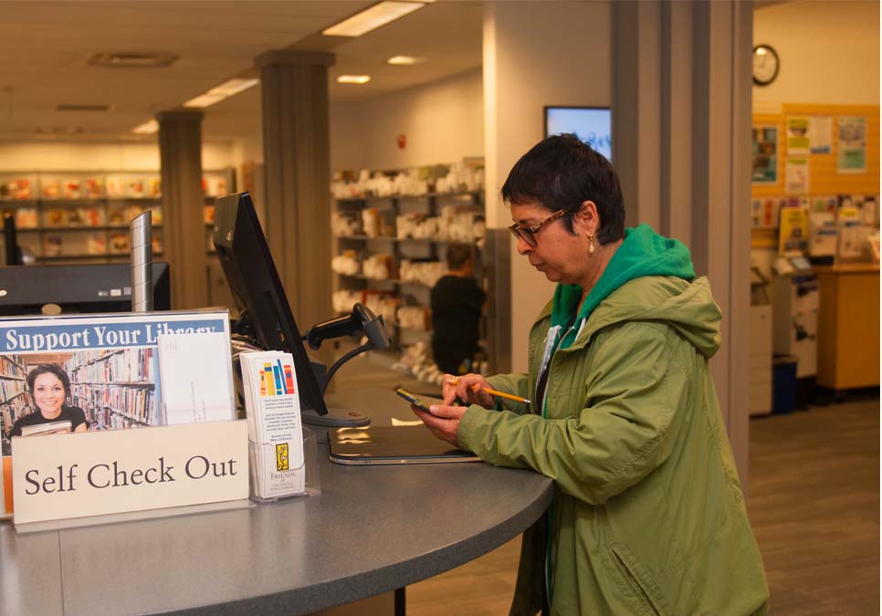 Library patron at self-checkout station at the Rainier Beach Branch 